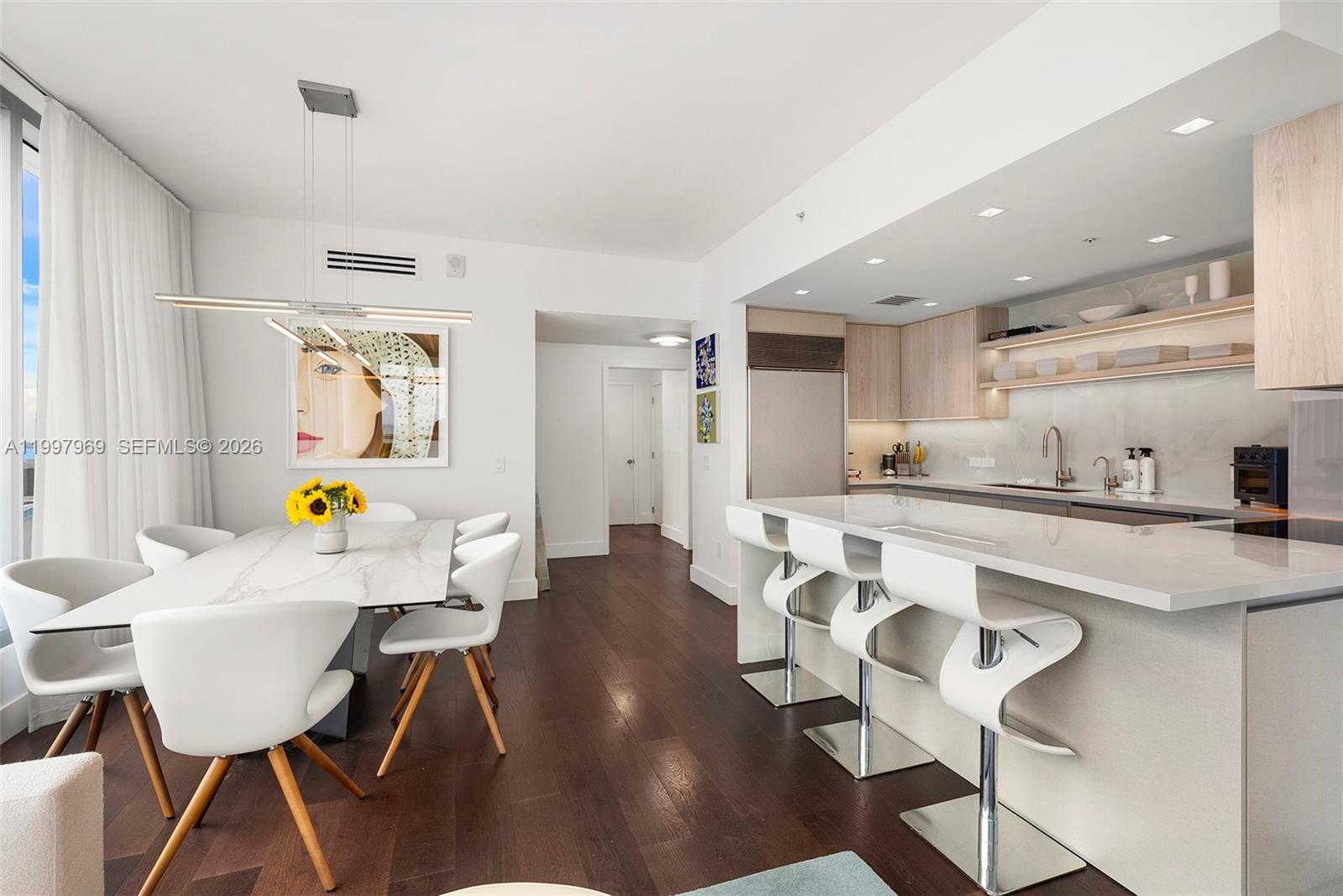 6899 Collins Avenue, Unit 1908 Miami Beach, FL 33141 - Photo 15 of 63 a kitchen with stainless steel appliances a dining table chairs and a refrigerator