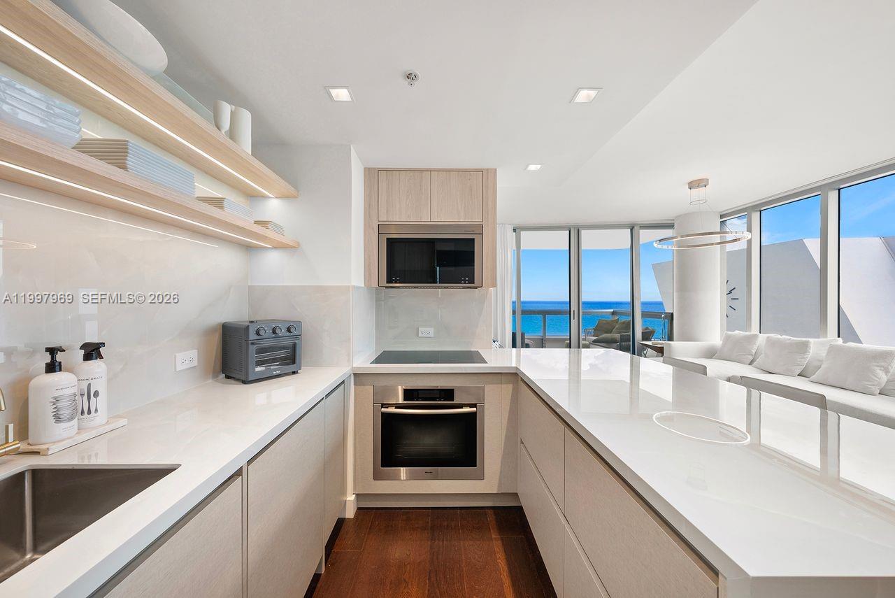 6899 Collins Avenue, Unit 1908 Miami Beach, FL 33141 - Photo 25 of 63 a large kitchen with a large counter top a stove a sink and a refrigerator