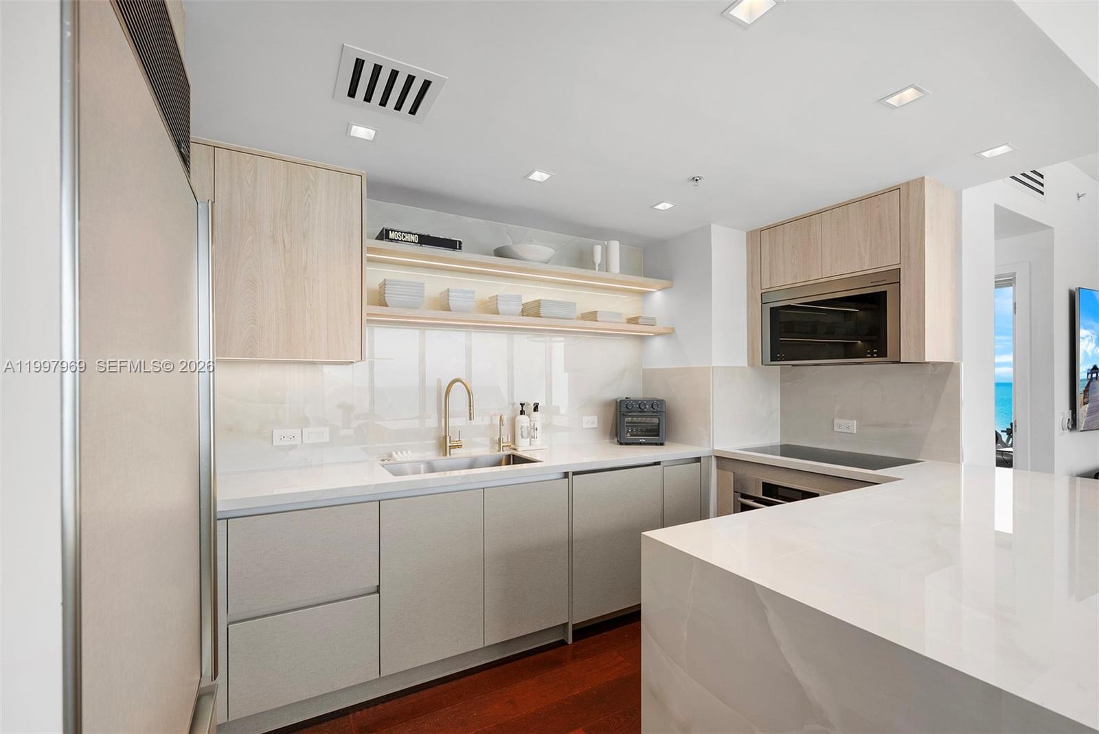 6899 Collins Avenue, Unit 1908 Miami Beach, FL 33141 - Photo 26 of 63 a kitchen with a sink stainless steel appliances and white cabinets