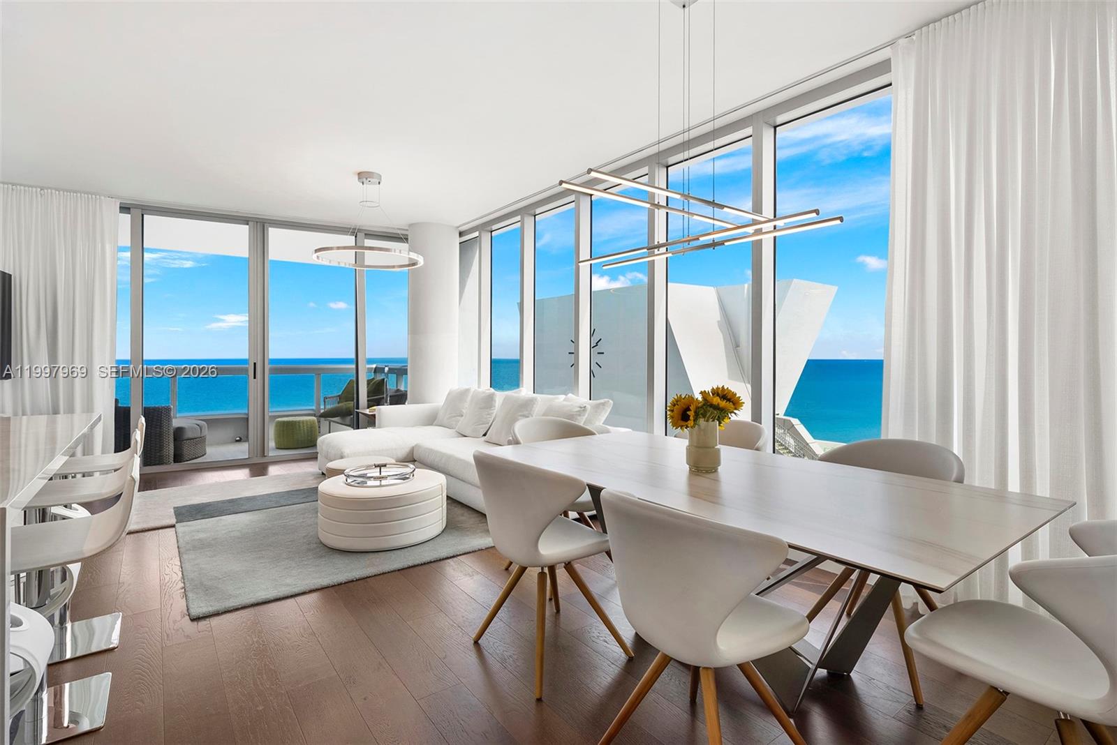 6899 Collins Avenue, Unit 1908 Miami Beach, FL 33141 - Photo 33 of 63 a view of a dining room with furniture large windows and wooden floor