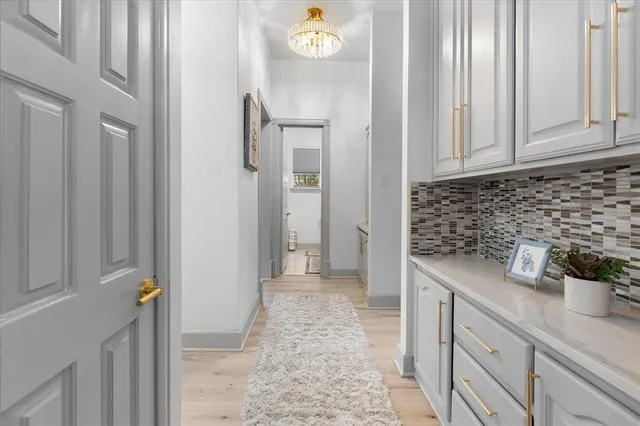 a view of a hallway with cabinets and wooden floor