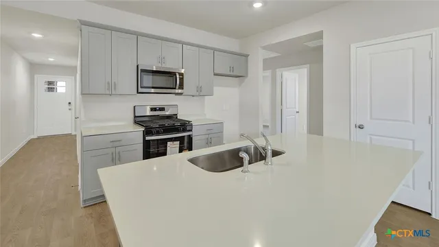 a kitchen with granite countertop a sink a stove and refrigerator