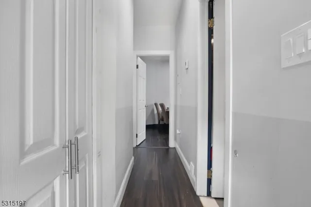 a view of a hallway with wooden floor and a bathroom