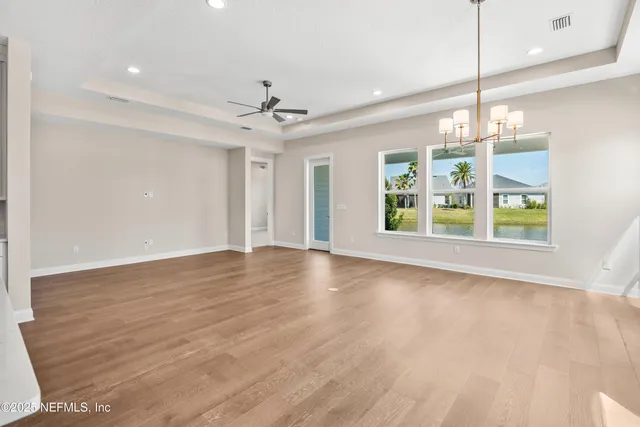 a view of an empty room with window and wooden floor