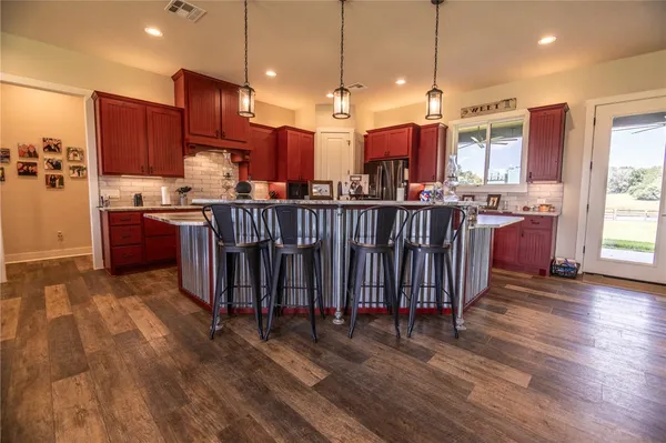 a kitchen with stainless steel appliances granite countertop a stove top oven a sink dishwasher and a dining table with wooden floor