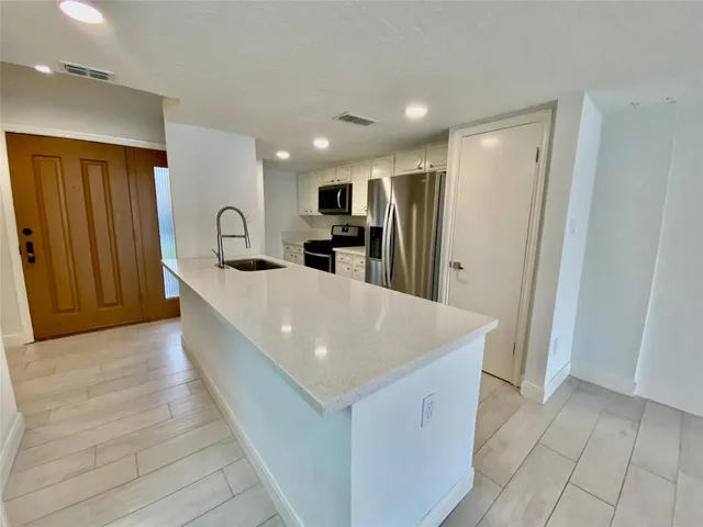 a large kitchen with stainless steel appliances a large counter top a refrigerator and a sink