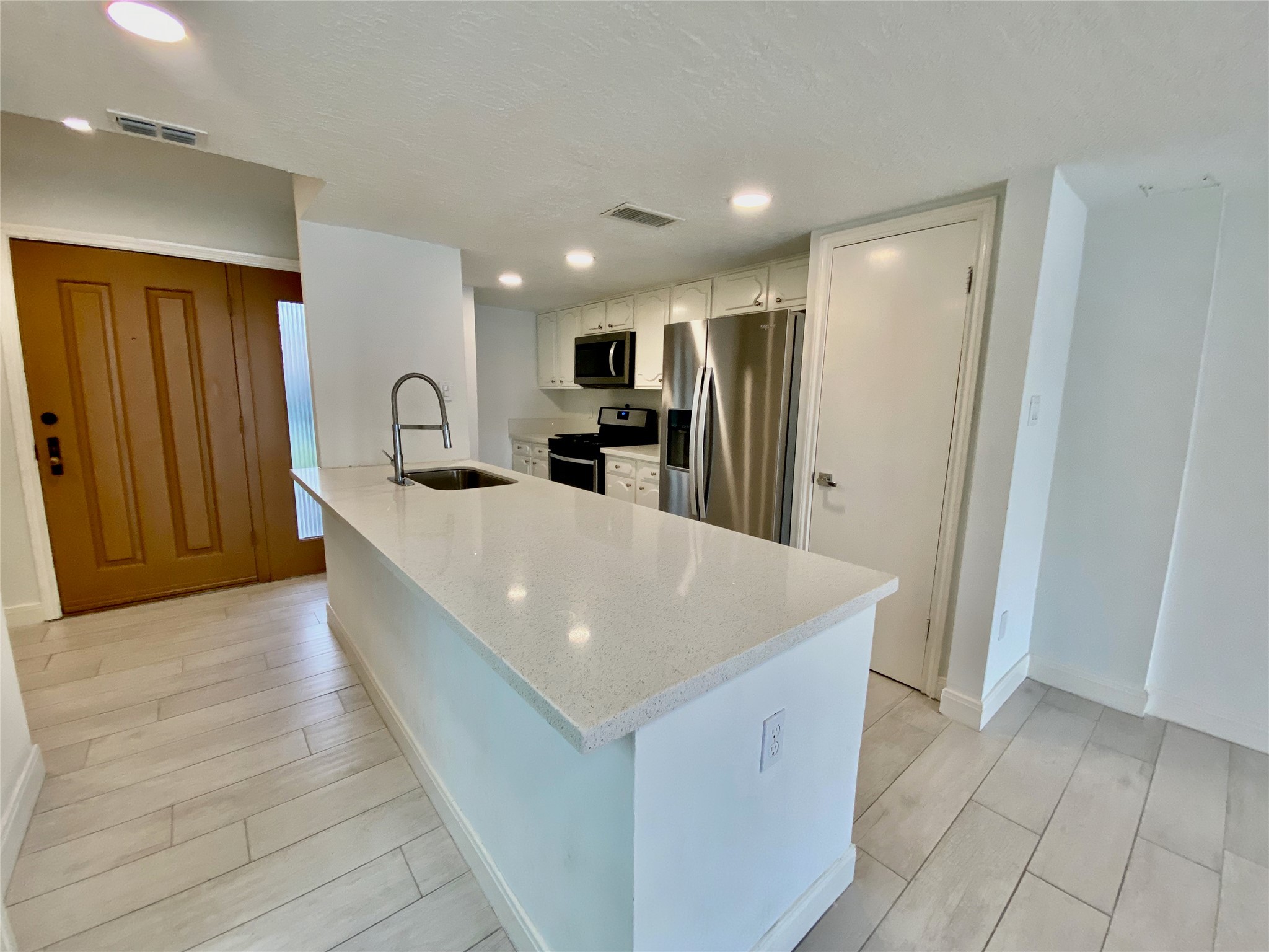 a large kitchen with stainless steel appliances a large counter top a refrigerator and a sink