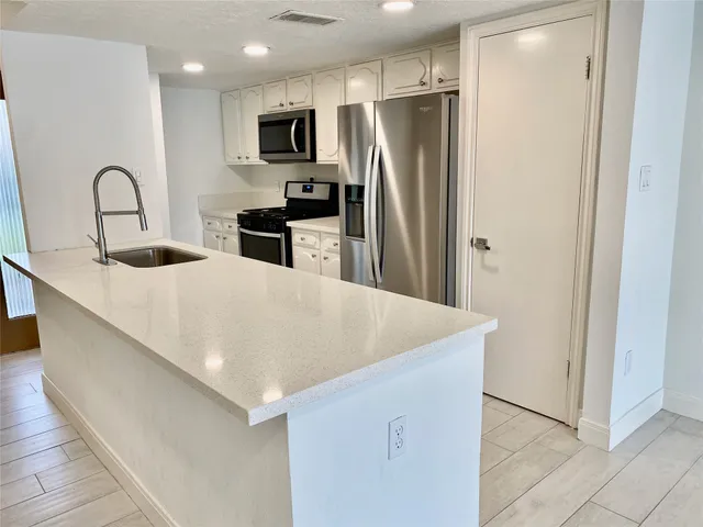 a kitchen with stainless steel appliances a refrigerator sink and microwave