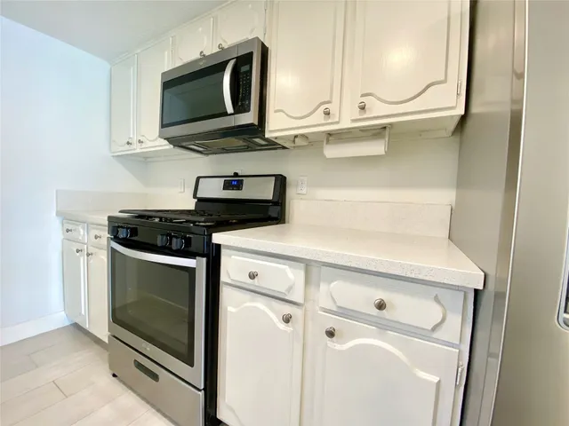 a kitchen with stainless steel appliances white cabinets and a stove top oven