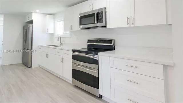 a kitchen with cabinets stainless steel appliances and wooden floor