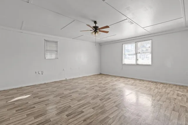 an empty room with windows and fan