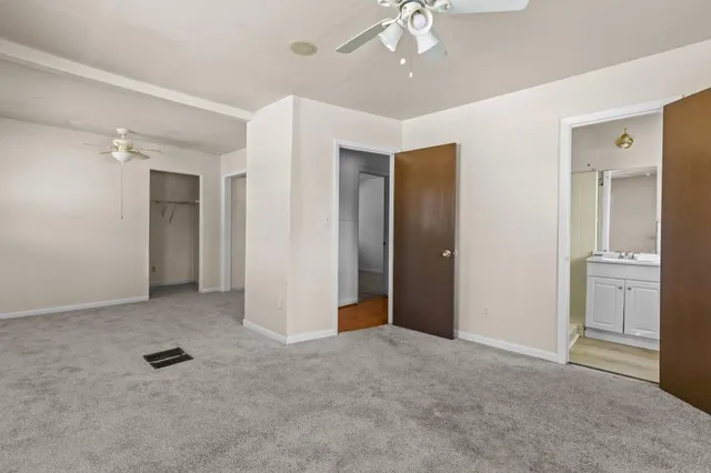 an empty room with closet and a chandelier fan