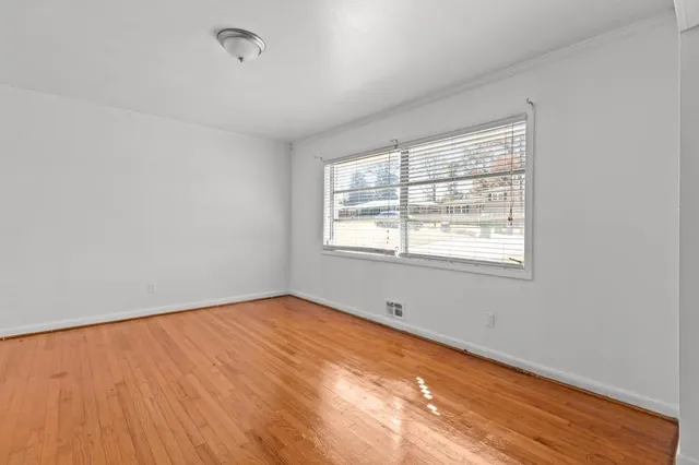 a view of an empty room with wooden floor and a window
