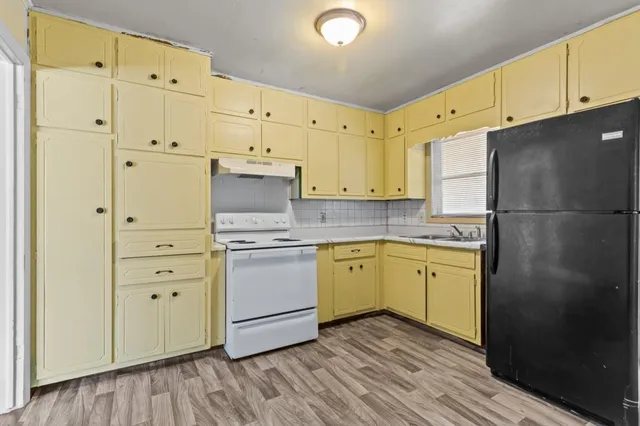 a kitchen with granite countertop white cabinets and refrigerator