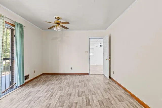 an empty room with wooden floor fan and windows