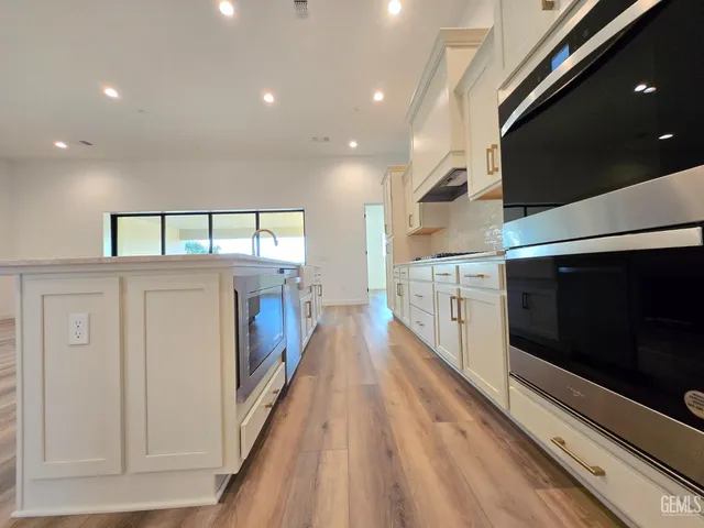 a view of a kitchen with a sink and dishwasher a stove top oven with wooden floor