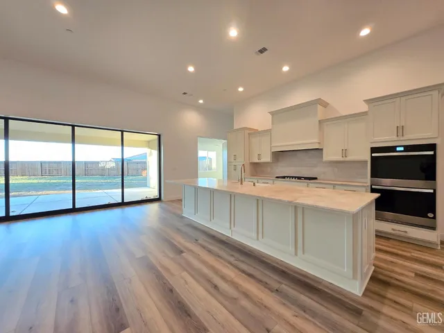 a large kitchen with stainless steel appliances a large counter top a stove and a sink