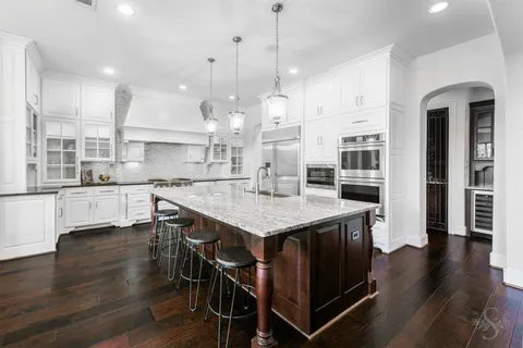 a open kitchen with stainless steel appliances granite countertop a stove a refrigerator a kitchen island a dining table and chairs with wooden floor