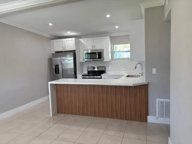 a kitchen with kitchen island white cabinets and refrigerator