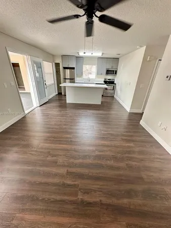 a view of kitchen and empty room with wooden floor