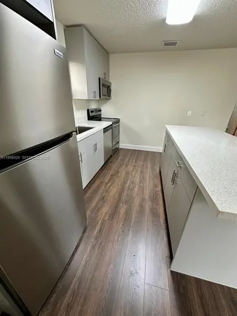 a view of a kitchen with wooden floor and electronic appliances