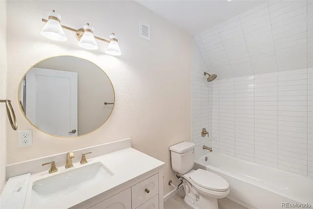 a bathroom with a toilet sink vanity tub and mirror