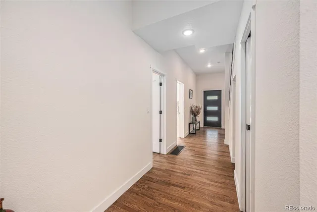 a view of a hallway with wooden floor an entryway and livingroom