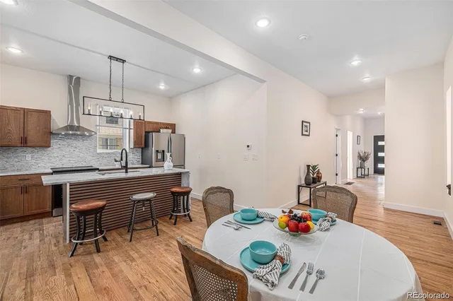 a kitchen with stainless steel appliances granite countertop a kitchen island a stove a dining table and chairs with wooden floor