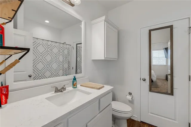 a bathroom with a granite countertop sink a toilet and a mirror