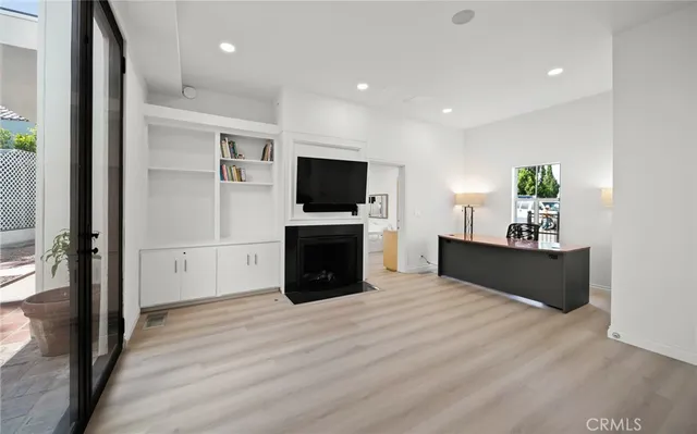 a kitchen with stainless steel appliances kitchen island granite countertop a refrigerator a stove a sink and white cabinets with wooden floor