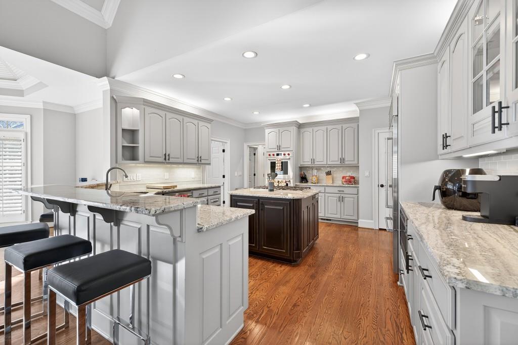 2761 Calloway Court Duluth, GA 30097 - Photo 19 of 124 a kitchen with stainless steel appliances kitchen island granite countertop a stove a sink a refrigerator and white cabinets with wooden floor