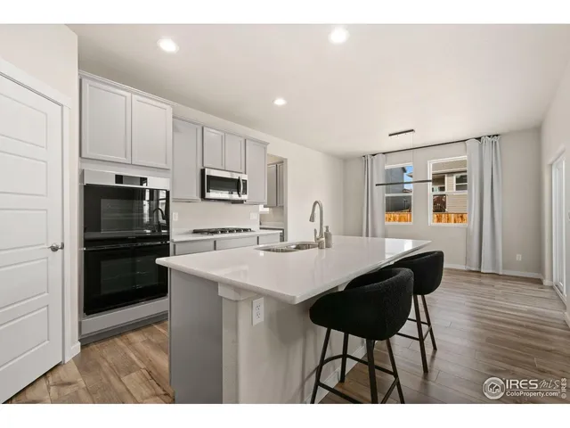 a kitchen with stainless steel appliances a table chairs and a refrigerator