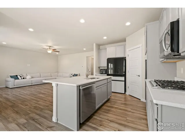 a large kitchen with kitchen island a stove a sink dishwasher and a refrigerator with wooden floor