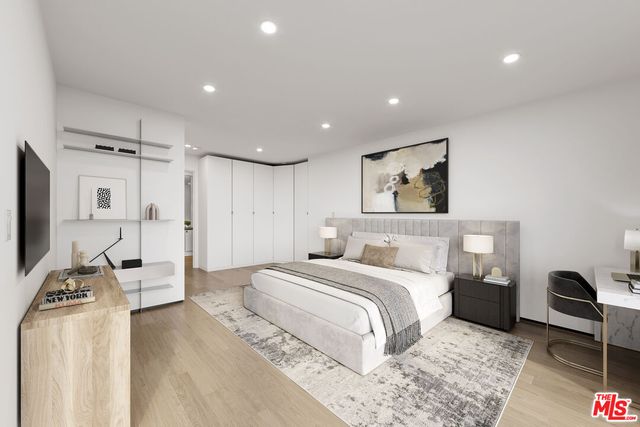 a spacious bedroom with a bed a couch and a flat tv screen