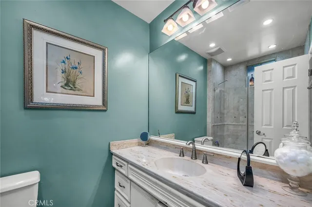 a bathroom with a granite countertop sink a toilet and a mirror