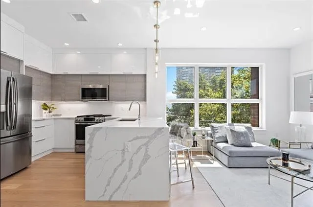 a living room with stainless steel appliances kitchen island granite countertop a refrigerator a stove top oven a sink dishwasher and a dining table with wooden floor