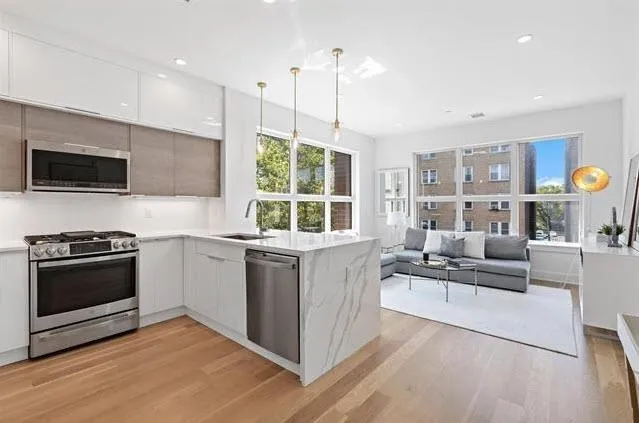 a living room with stainless steel appliances granite countertop a stove and a wooden floors