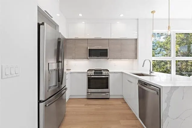 a kitchen with stainless steel appliances granite countertop a refrigerator a sink and a stove