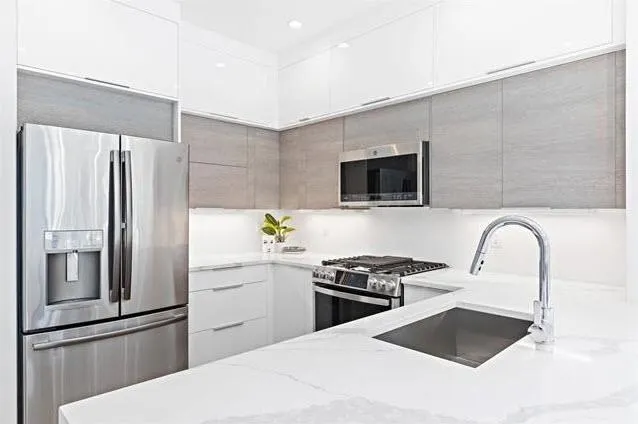 a kitchen with stainless steel appliances kitchen island a refrigerator sink and white cabinets