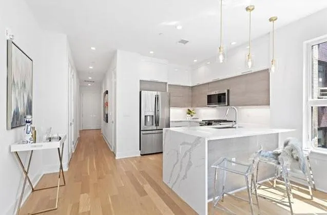 a large kitchen with stainless steel appliances kitchen island granite countertop a stove a sink a refrigerator and a refrigerator