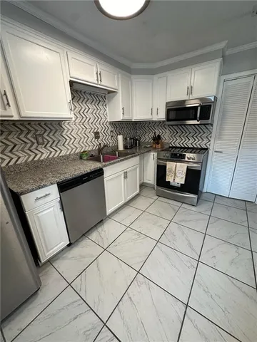 a kitchen with granite countertop a sink a stove top oven and cabinets
