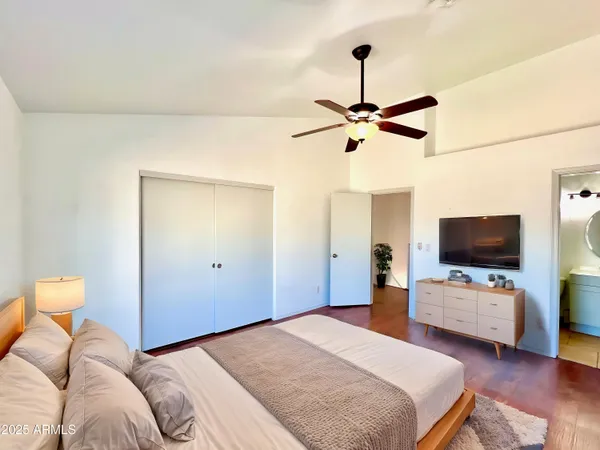 a bedroom with a bed and a flat tv screen on a dresser