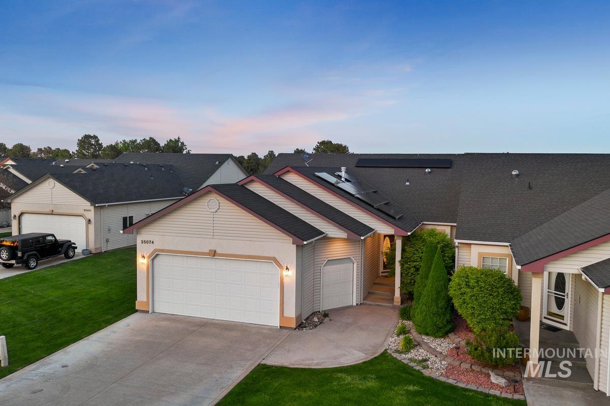 25074 The Driving Lane Caldwell, ID 83607 - Photo 4 of 32 Contemporary residence featuring a two-car garage with carriage-style doors, a concrete driveway, and a manicured lawn