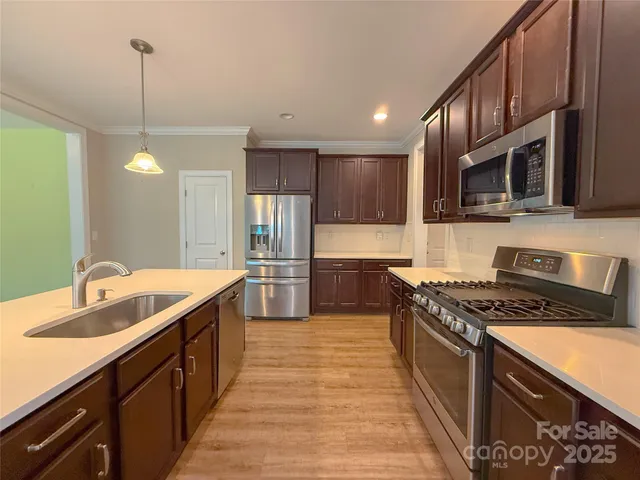 a kitchen with stainless steel appliances granite countertop a sink a stove and a wooden floors