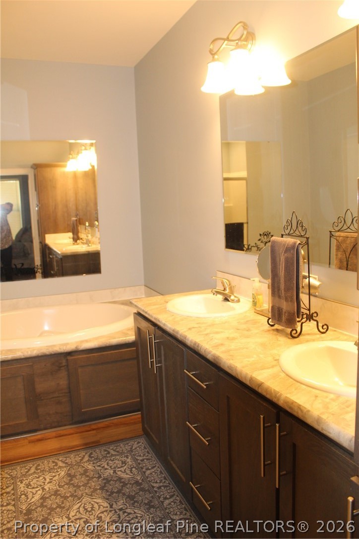 951 Lucian Hilliard Road Goldston, NC 27252 - Photo 15 of 25 a bathroom with a granite countertop sink and a bathtub