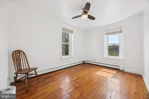 a view of empty room with wooden floor and fan