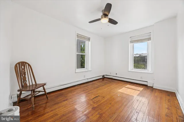 a view of empty room with wooden floor and fan