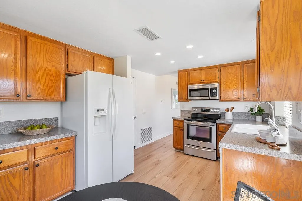 13489 Ridley Road San Diego, CA 92129 - Photo 13 of 36 a kitchen with stainless steel appliances granite countertop a refrigerator a stove top oven a sink and dishwasher