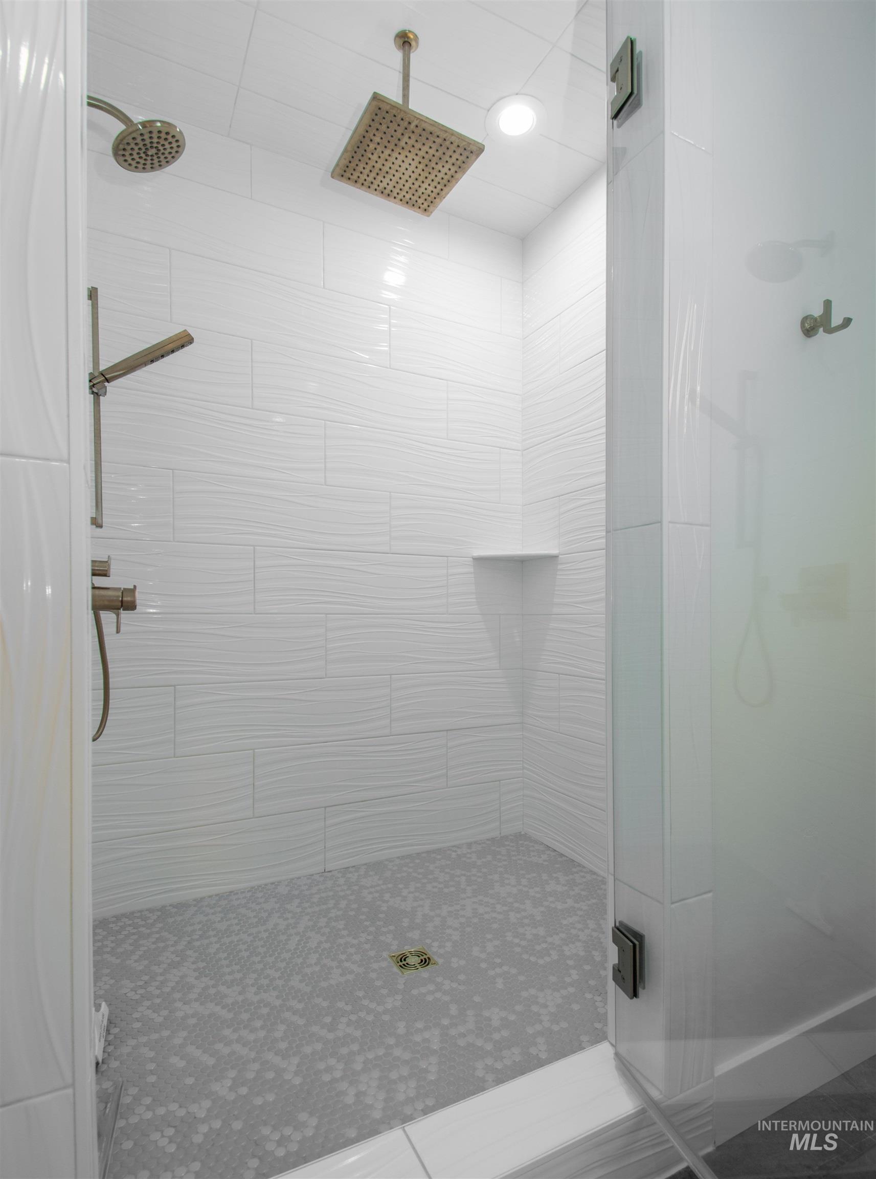 44 Big Moose Road McCall, ID 83638 - Photo 20 of 50 Walk-in shower featuring white wave-patterned wall tiles, a mosaic tile floor, and a built-in shower niche