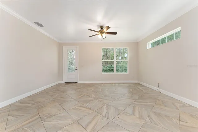 an empty room with windows and fan